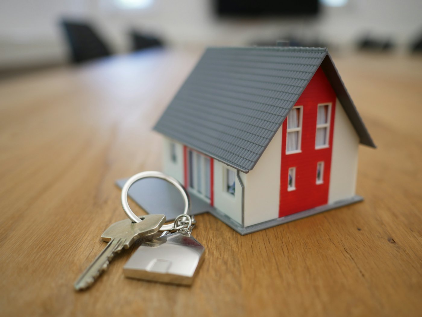 House keys beside a small model home on a table.