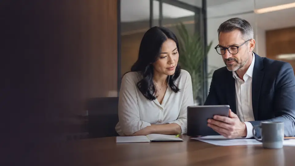 An advisor and a client reviewing documents together at a conference table.