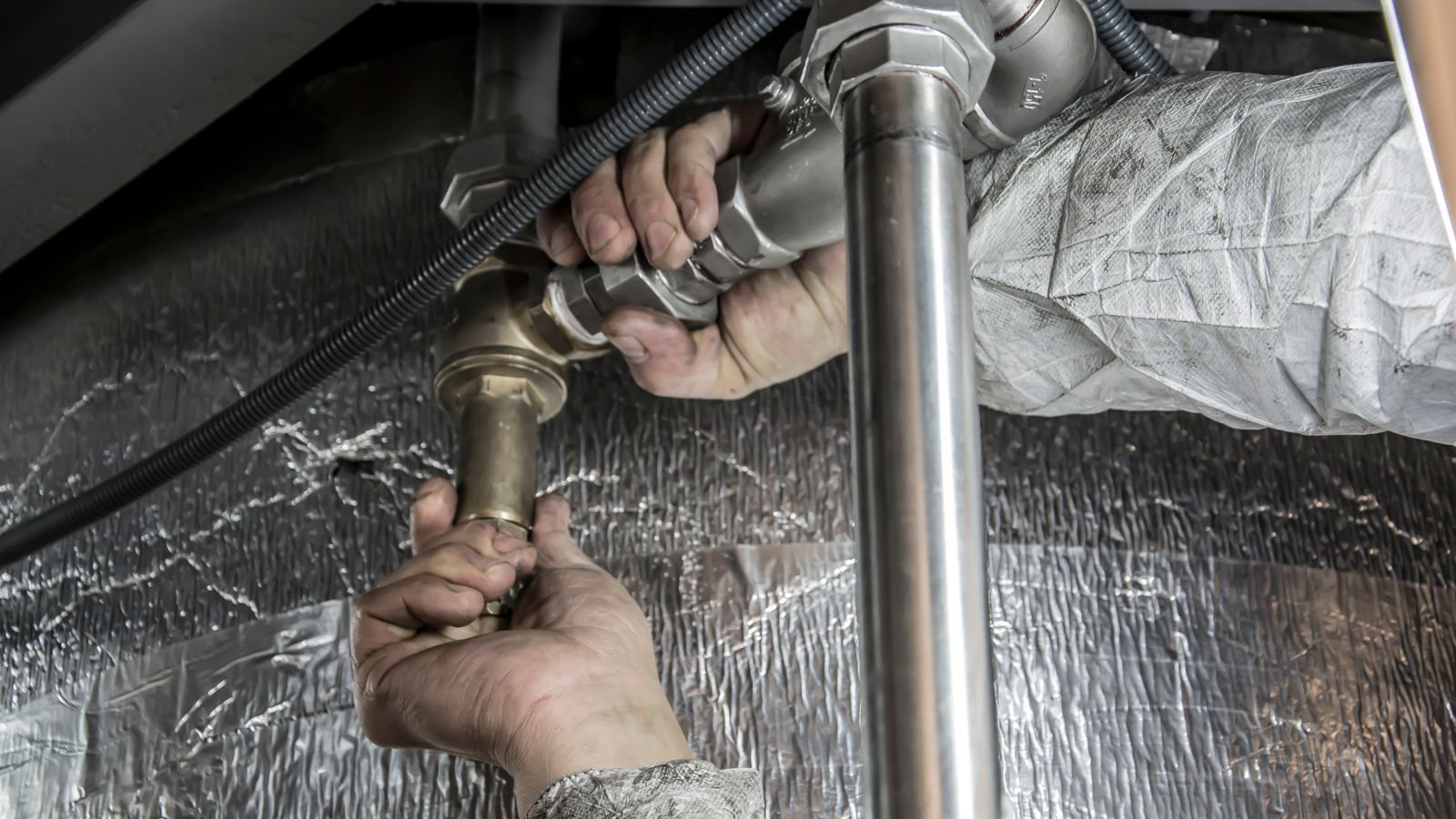 Plumber installing pipe fittings, illustrating plumber website design for Quad Cities service businesses