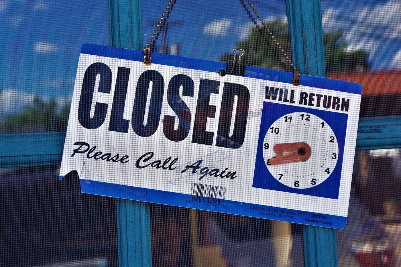 Closed sign with a will-return clock hanging in a shop window