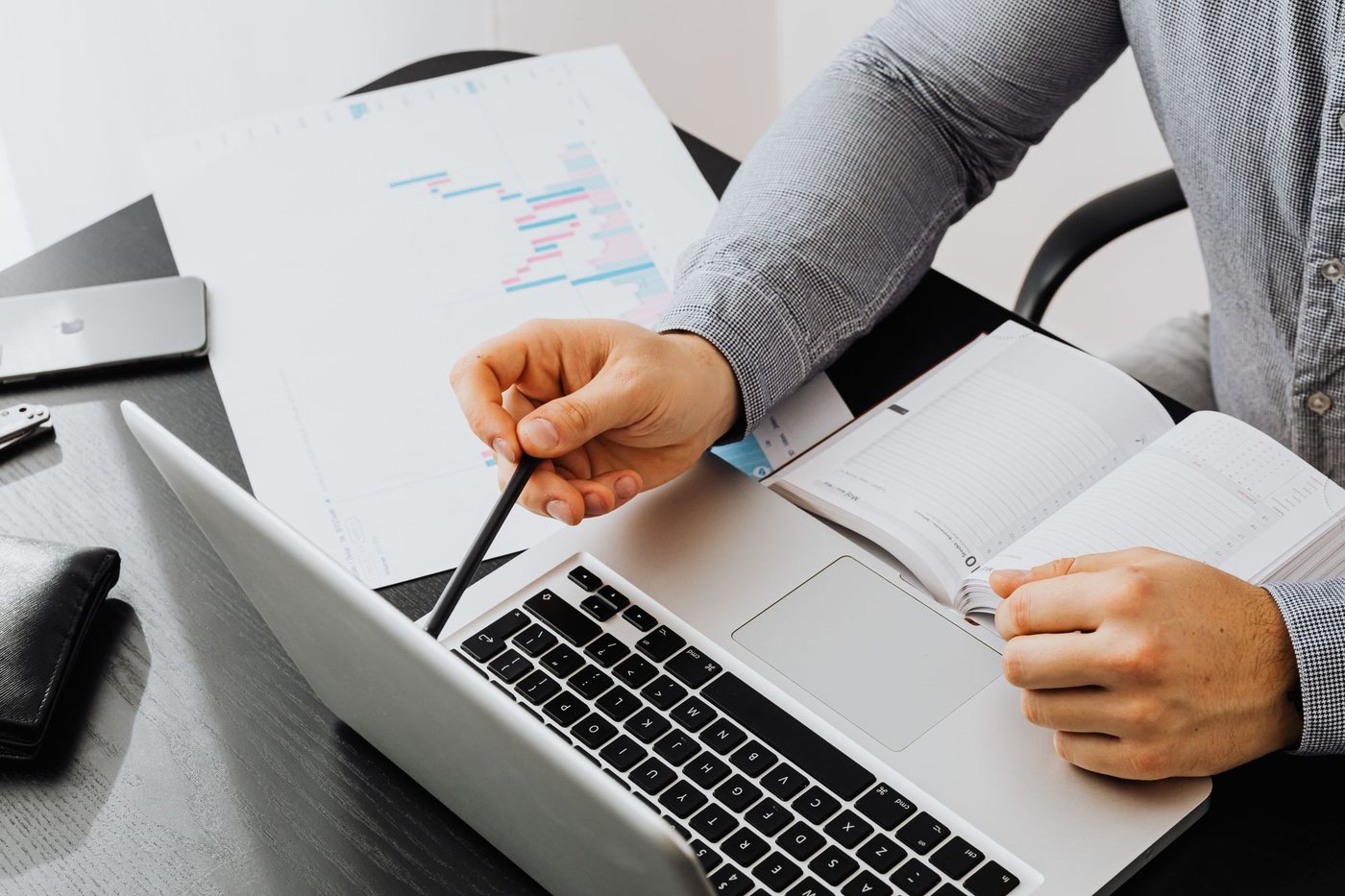 Hands marking up printed notes next to a laptop while revising written content