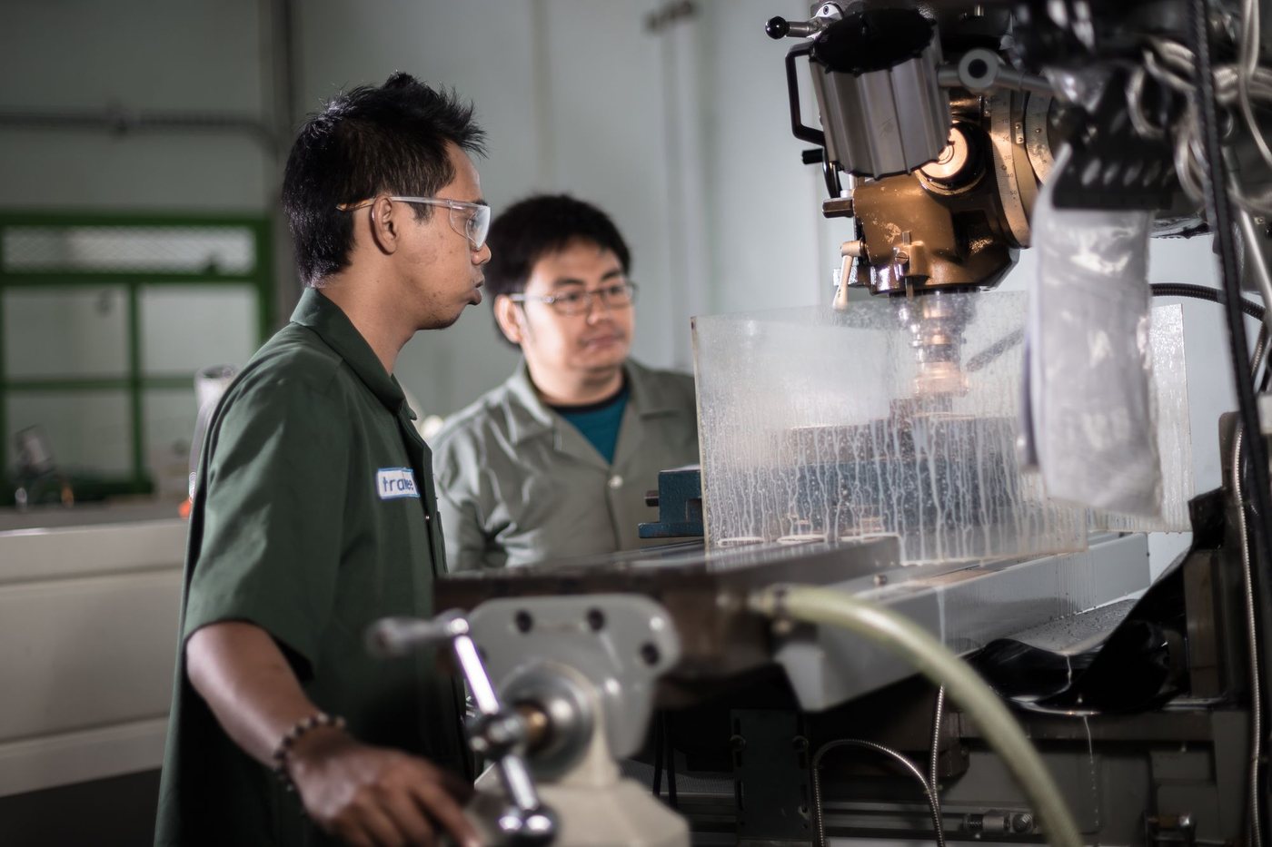 Two machinists inspecting a part at a CNC machine on a shop floor