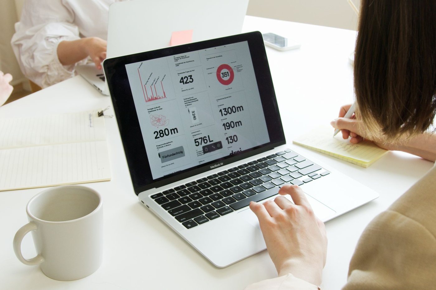Business owner reviewing a website analytics dashboard on a laptop with a notebook