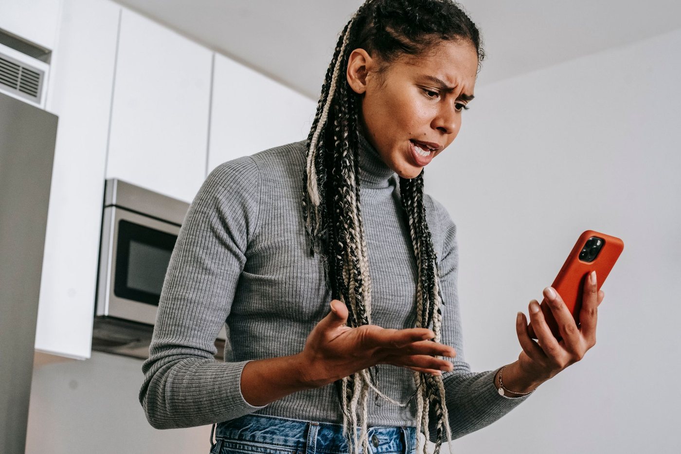Frustrated woman holding her phone up while waiting for a page to load