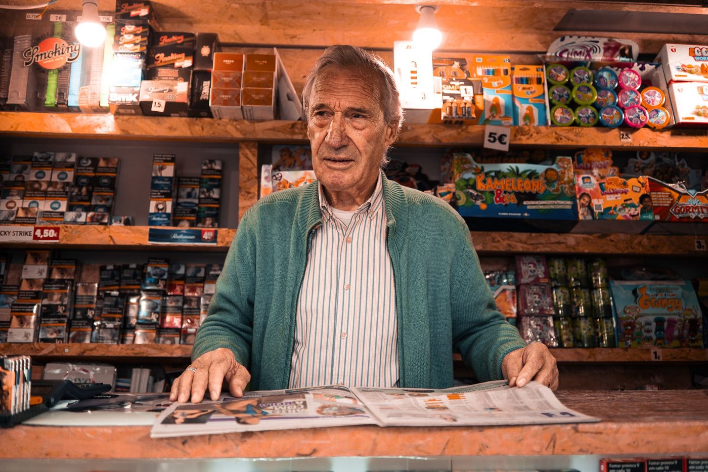 Shopkeeper standing behind the counter of a well-stocked small shop